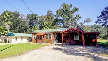 A two-story wooden house with a porch, a garage, and a gravel driveway.