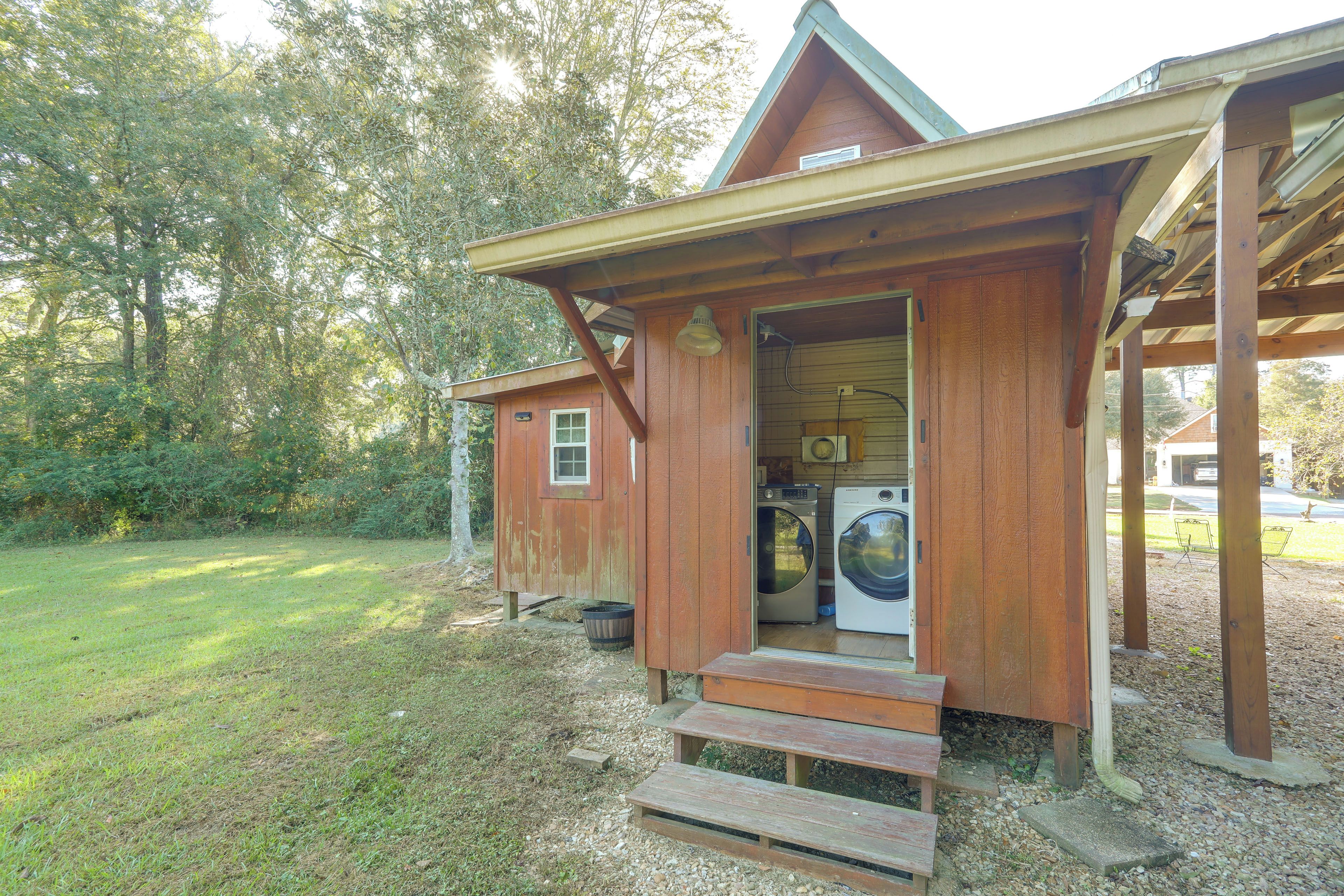 A wooden cabin with a laundry area, including a washing machine and dryer, and a small porch with steps leading to the entrance.