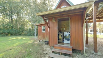 A wooden cabin with a laundry area, including a washing machine and dryer, and a small porch with steps leading to the entrance.