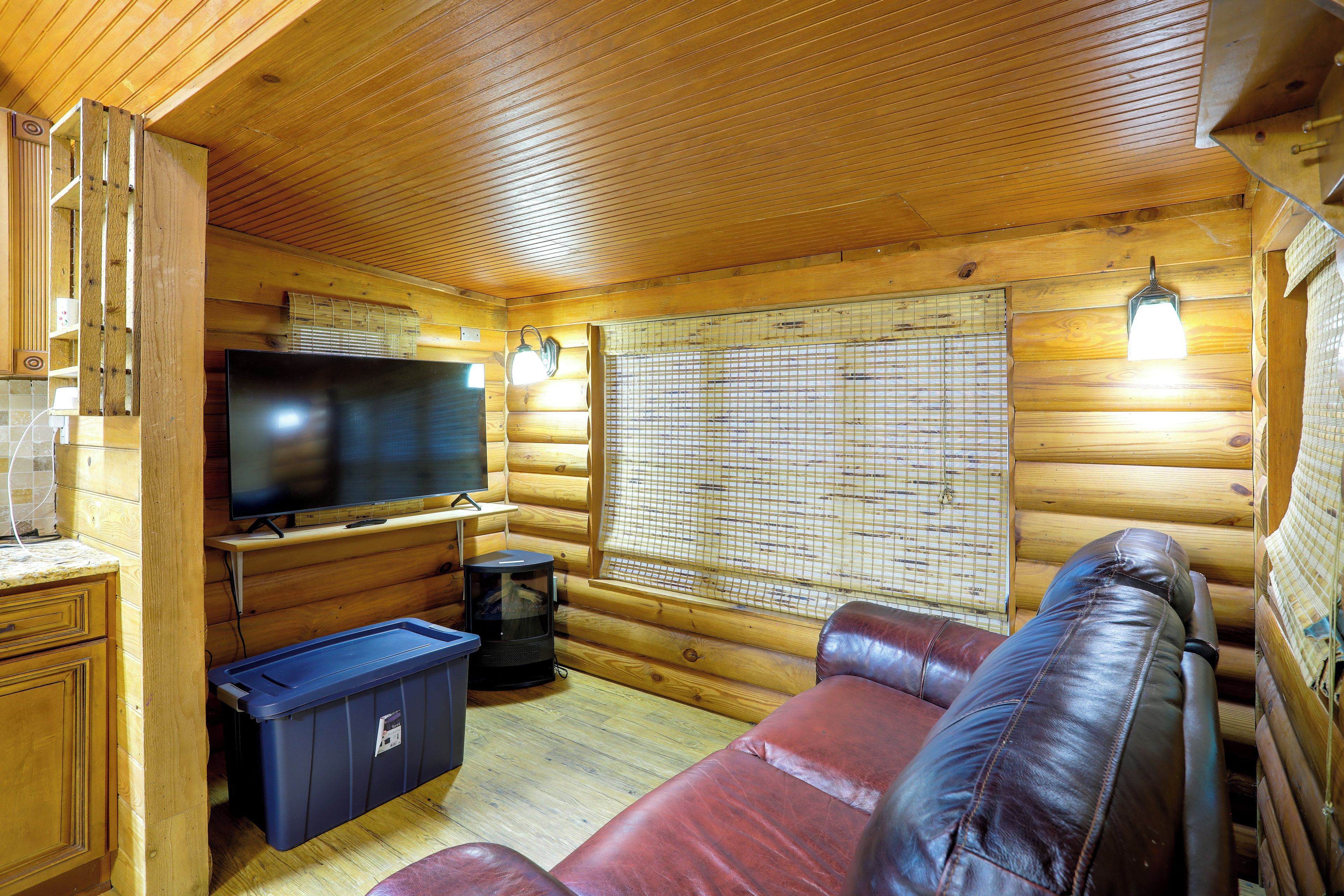 A log cabin interior with a television, seating area, and a window with blinds.