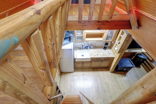 Une cuisine de taille réduite, équipée d’un réfrigérateur, d’un évier et de meubles de rangement en bois.