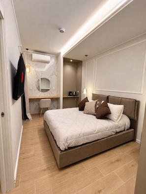 Een moderne slaapkamer met een groot bed, een bureau en een spiegel.