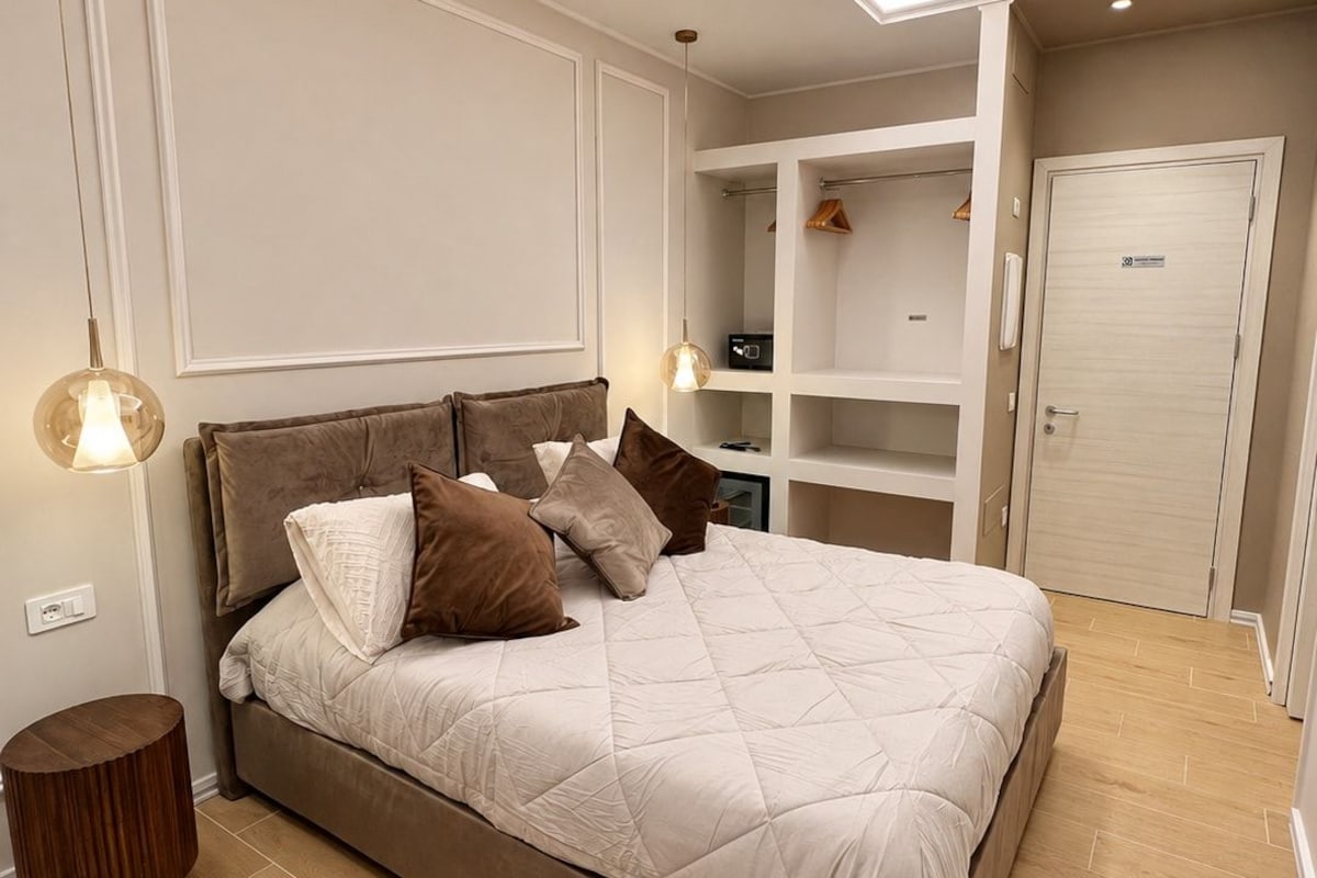 Een moderne slaapkamer met een groot bed, inbouwkasten en een inloopkast.