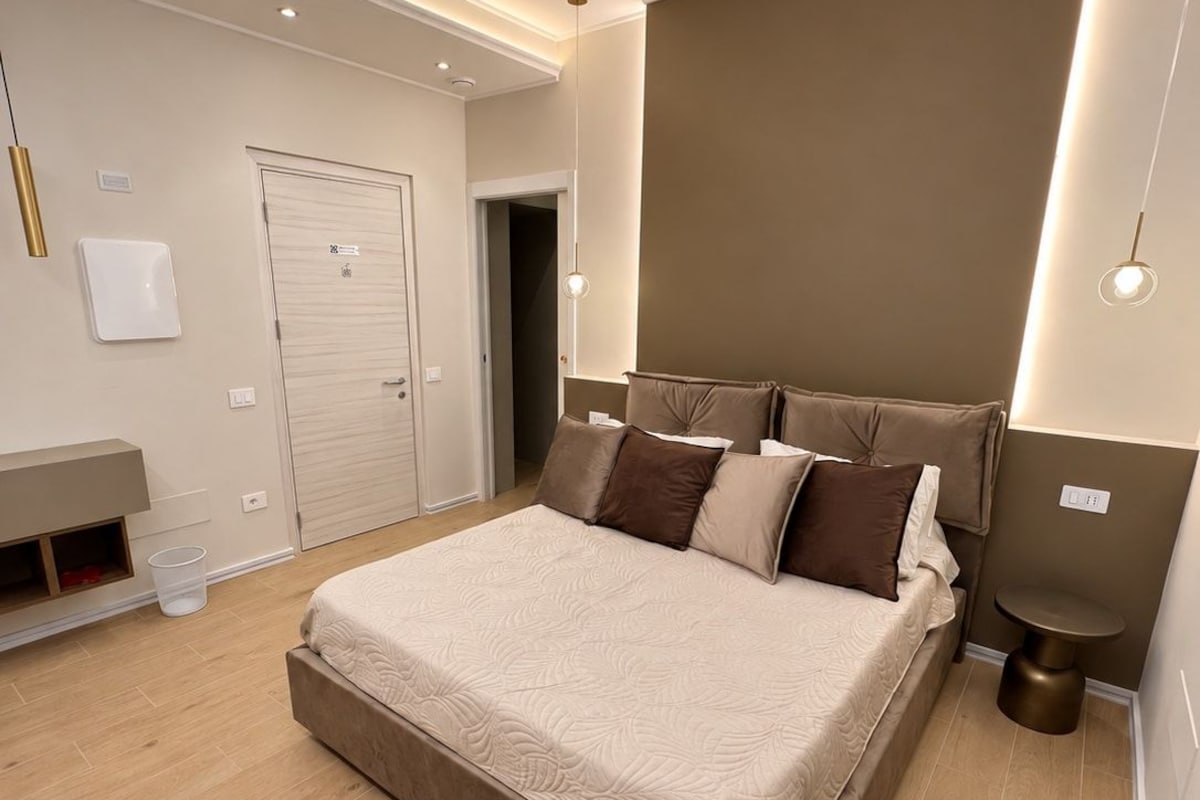 Een moderne slaapkamer met een groot bed, nachtkastjes, een kledingkast en een deur.