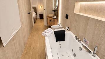 Un baño moderno con una bañera grande, un tocador con espejo y un armario de madera.