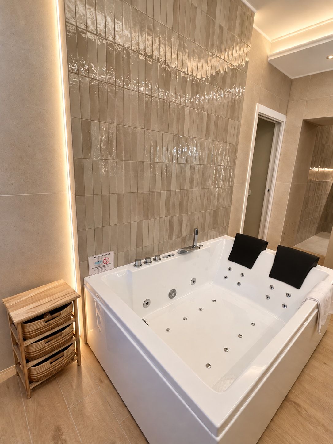 Ein modernes Badezimmer mit einer großen weißen Badewanne, einem hölzernen Nachttisch und einer gefliesten Wand mit einem einzigartigen Muster.
