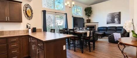 A spacious living area with a dining table, a fireplace, and a large window.