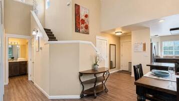 A spacious living area with a staircase, a dining table, and a kitchen area.