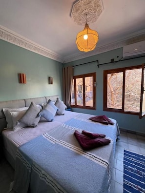 A hotel room with a large bed, a ceiling light fixture, and a window with curtains. - La Perle De Neige (Imlil)