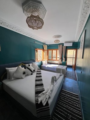 A hotel room with a large bed, a smaller bed, a window with curtains, and a decorative ceiling light. - La Perle De Neige (Imlil)