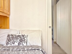 Un dormitori amb llit, dos plomalls, un armari de fusta i una porta que dona a un bany.