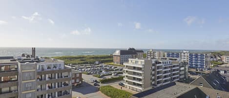 Zona residencial costera con edificios de varios pisos, un estacionamiento y vista al mar.