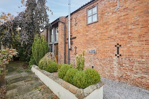 A brick building with a garden area featuring neatly trimmed bushes and a stone pathway. - Host Stay - Ruby s Retreat (York)
