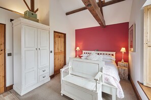 A bedroom with a white bed, a red wall, and a large white wardrobe. - Host Stay - Ruby s Retreat (York)