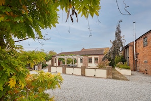 Ein Innenhof mit einer Pergola, Backsteingebäuden und Kiesboden.