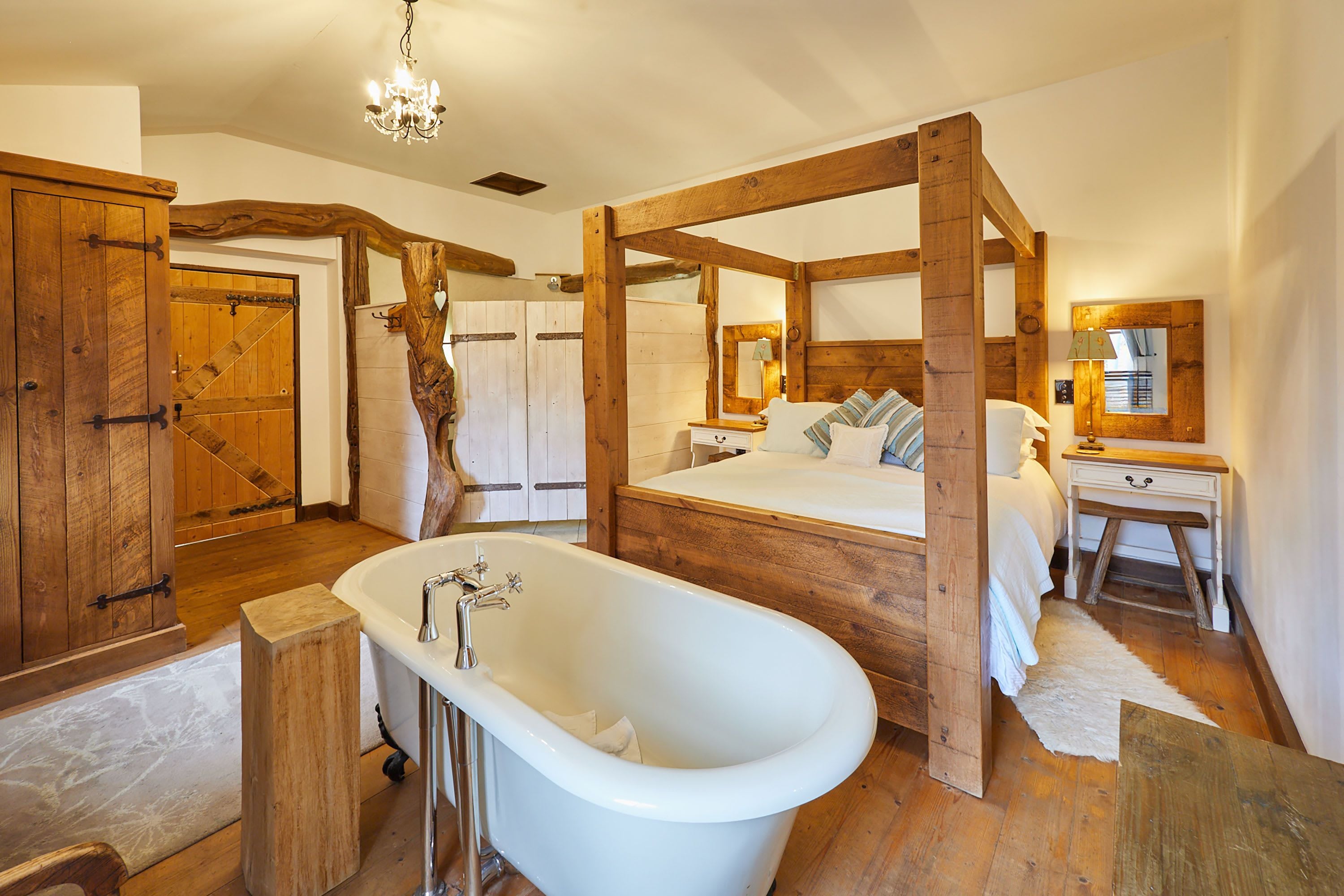 A rustic bathroom with a freestanding bathtub, wooden beams, and a large mirror.