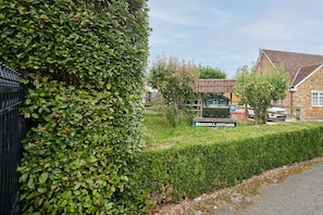 Ein von Hecken gesäumter Weg führt zu einem Anwesen mit einem Schild, auf dem 'Bricknell Cottages' steht.