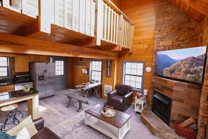 Un intérieur de chalet chaleureux comprenant une cuisine, un coin repas, un salon et une cheminée.
