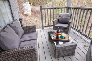 Un espace extérieur aménagé, abrité et doté de meubles en osier, avec une table où sont disposés des collations, des boissons et une bouteille.