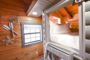 Ein Ferienhäuschen mit einem Bett, einem Fenster und Holzwänden.