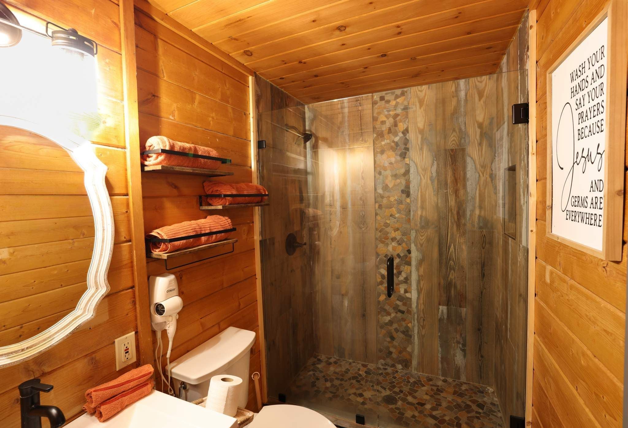 A wooden interior with a shower, toilet, and towel rack.