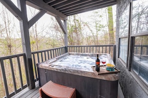 A hot tub with a wooden deck, a bottle, and snacks on a tray. - Hero s Peak - Theater Arcade Hot Tub (Sevierville)