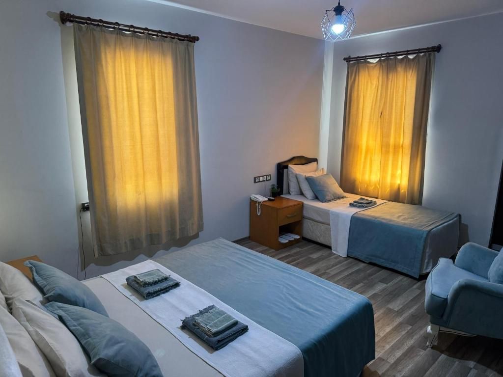 Una habitación de hotel con dos camas, una mesita de noche, una silla y cortinas.
