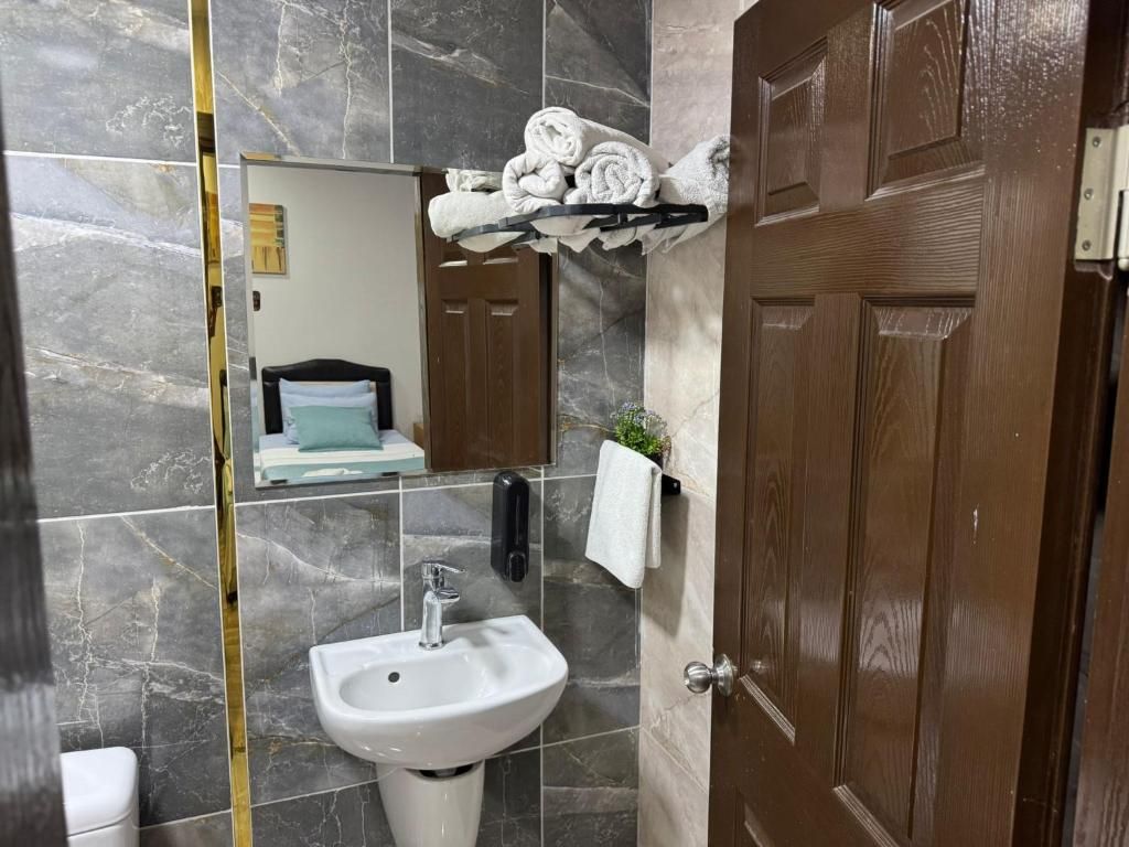 A bathroom with a marble wall, a sink, a towel rack, and a wooden door.