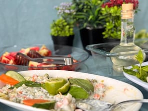 Una mesa con diferentes platos, una botella de vidrio y plantas en macetas.