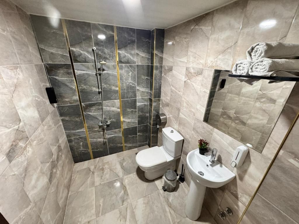 A bathroom with a shower, toilet, sink, and a mirror.