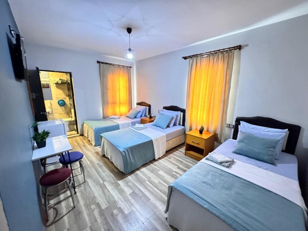 A hotel room with two single beds, a desk with a chair, and a small table.
