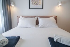 A hotel room with a large bed, two bedside lamps, a framed artwork on the wall, and a window with curtains. - Supernova DeLuxe Residence 2bdr Apartment in Novi Sad with AC for relaxing stays (Novi Sad)