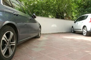 A parking area with two cars parked adjacent to a white wall. - Supernova DeLuxe Residence 2bdr Apartment in Novi Sad with AC for relaxing stays (Novi Sad)