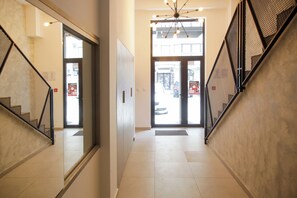 A hallway with a mirrored wall, a staircase with a metal railing, and a door leading outside. - Supernova DeLuxe Residence 2bdr Apartment in Novi Sad with AC for relaxing stays (Novi Sad)