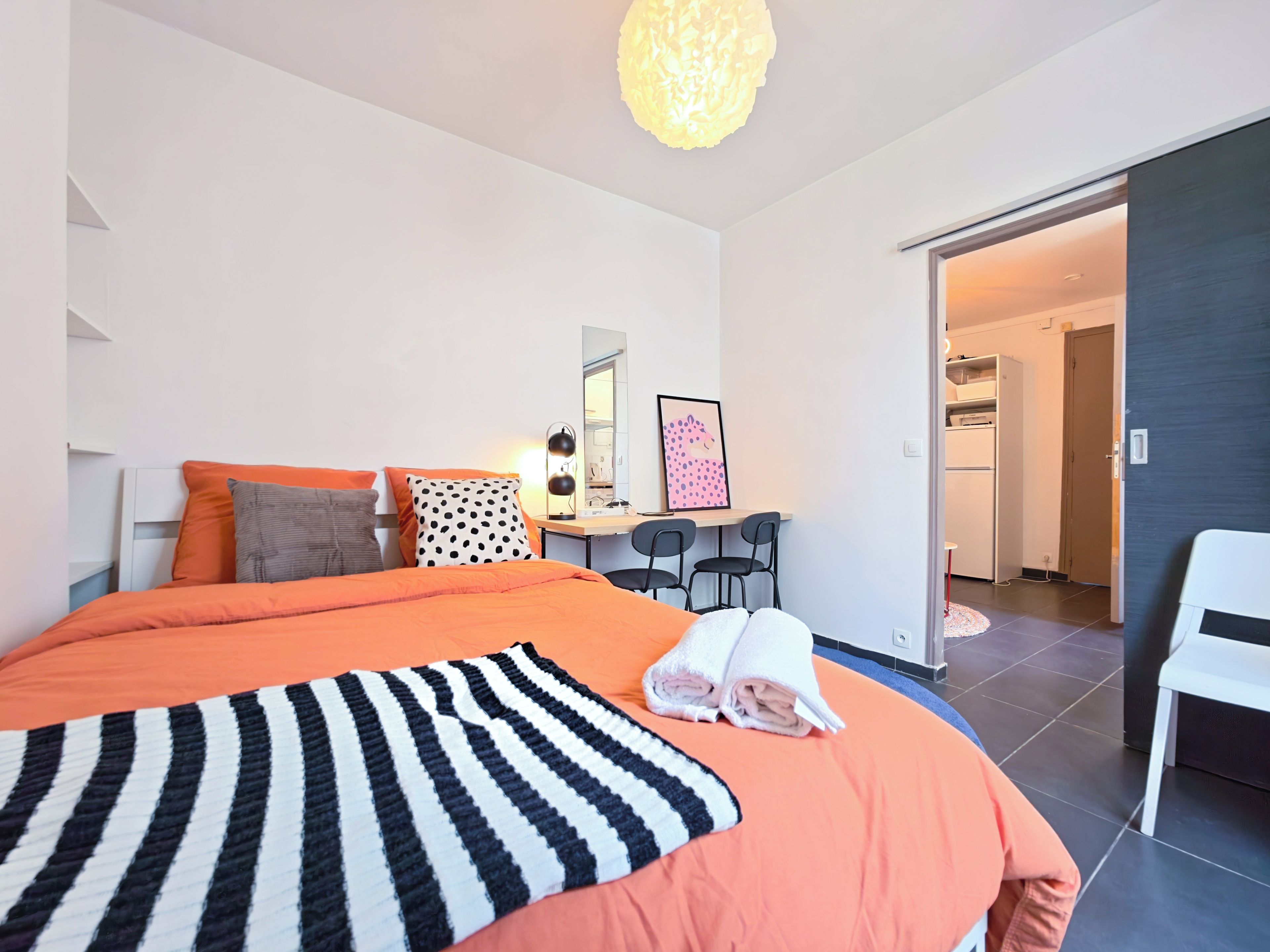 A modern bedroom with a large bed, a desk, and a chair.