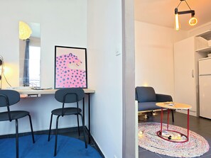 A modern living space with a desk, chairs, a sofa, and a kitchen area. - New Listing (Paris)