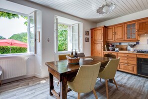 A dining area with a wooden table, two chairs, and a red umbrella outside. - New Listing (Saint-Cirgues-de-Malbert)