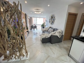 A modern living room with a grey sofa, a wooden decorative piece, and a dining area with chairs and a table. - New Listing (Benidorm)