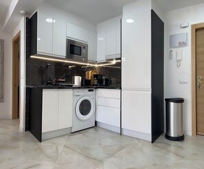A compact kitchen with a washing machine, microwave, and a coffee maker. - New Listing (Benidorm)