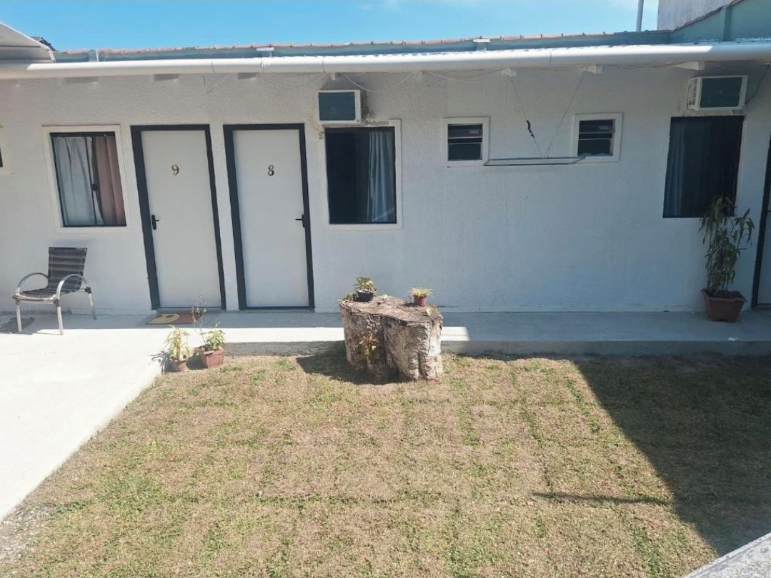 A building with two doors, numbered 9 and 8, a small outdoor seating area with a bench, and a tree stump.