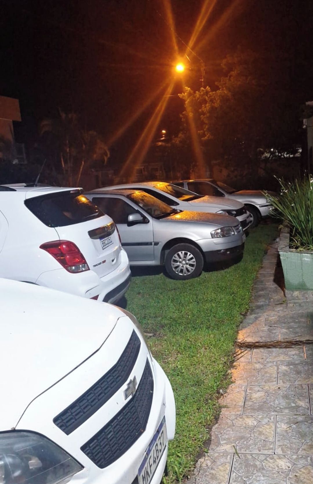 A row of parked cars along a paved path with a streetlight in the background.