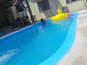 Una piscina con juguetes inflables y una persona en el agua.