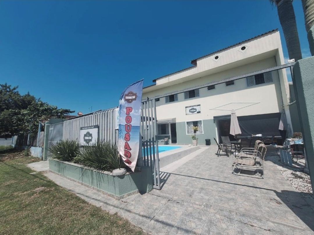 Un bâtiment doté d’une piscine, d’un espace extérieur aménagé et d’un drapeau sur lequel est inscrit le mot « POSADO ».
