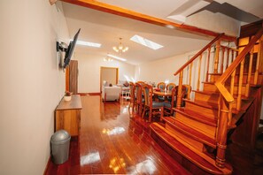 A spacious room with a wooden staircase, a dining area with chairs and a table, and a large mirror on the wall. - New Listing (Cusco)