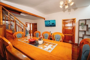 A dining area with a wooden table, chairs, and a television mounted on the wall. - New Listing (Cusco)