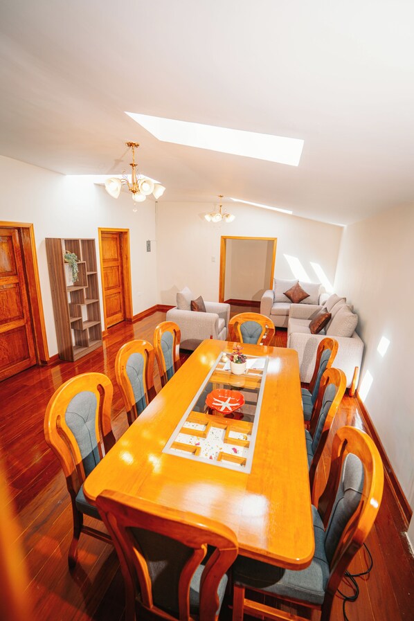 A spacious room with a long wooden dining table surrounded by chairs, a sofa, and a large mirror. - New Listing (Cusco)