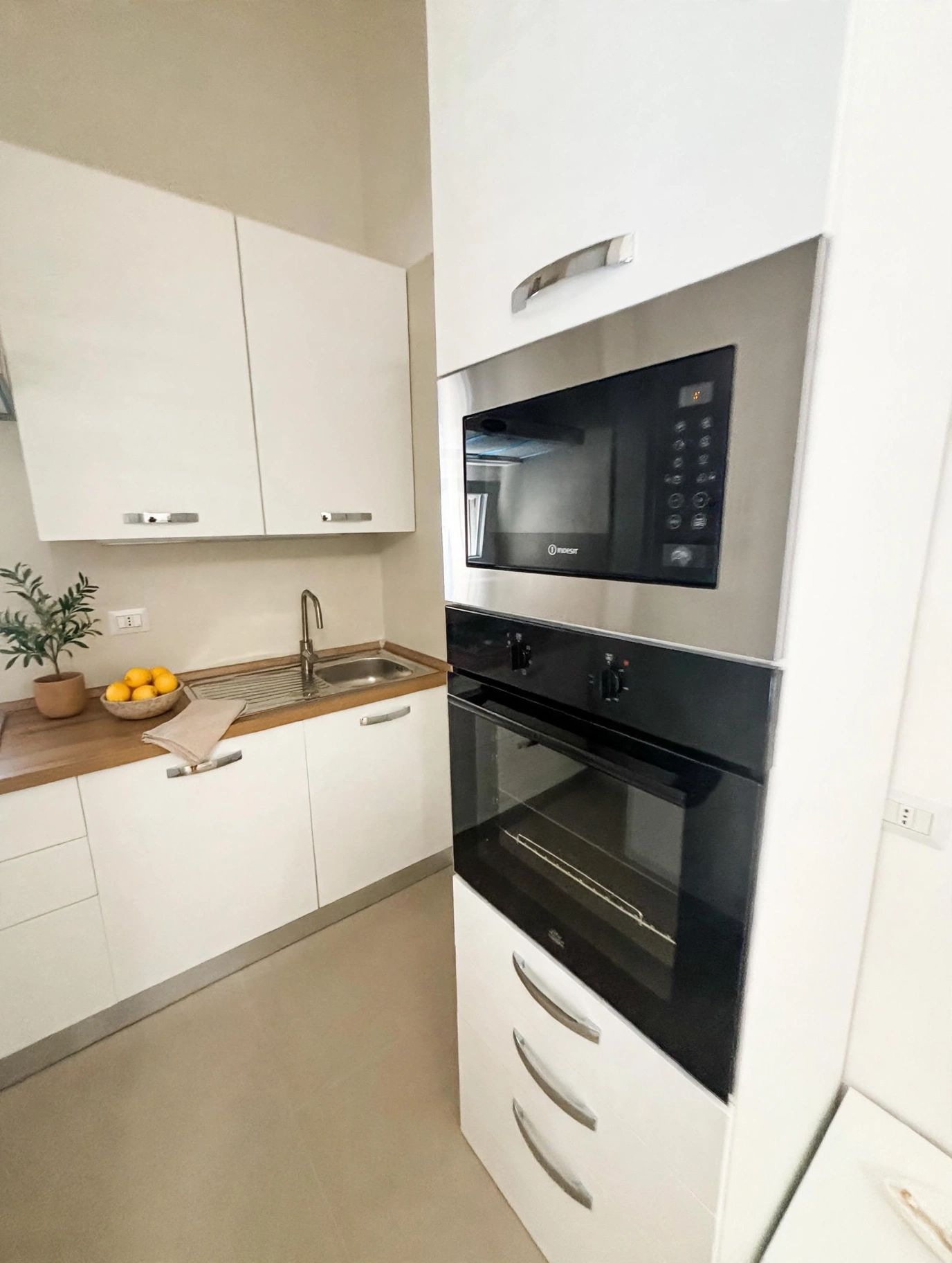 Eine moderne Küche mit weißen Schränken, einer Edelstahl-Mikrowelle und einem eingebauten Backofen.