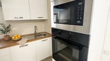 Eine moderne Küche mit weißen Schränken, einer Edelstahl-Mikrowelle und einem eingebauten Backofen.