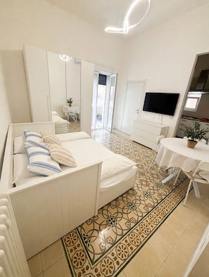 Een moderne slaapkamer met een bed, een televisie, een klein tafeltje en een badkamer.
