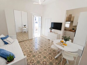 Ein modernes, helles Zimmer mit einem Bett, einem Esstisch und einem Fernseher.